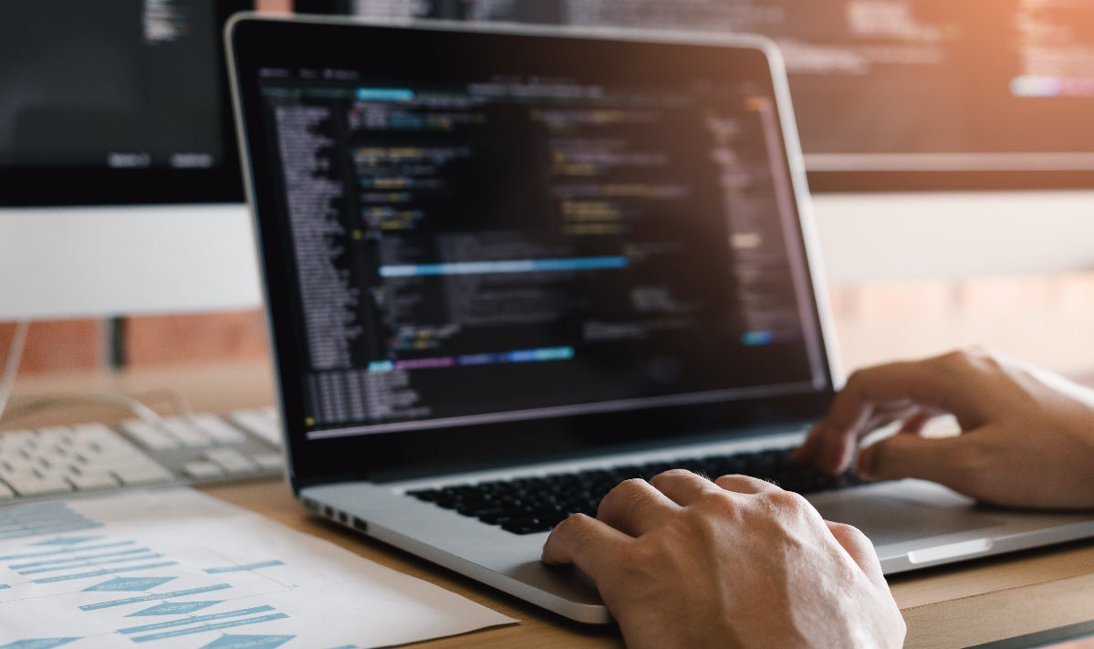A close up a persons hands typing on a laptop updating their firewall rules