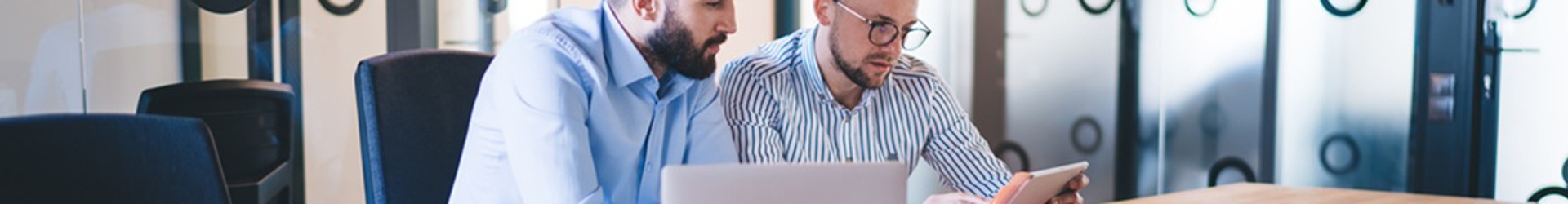 Two IT Team workers sitting at a board table reviewing their Incident Response Plan and Cyber Risk Register.