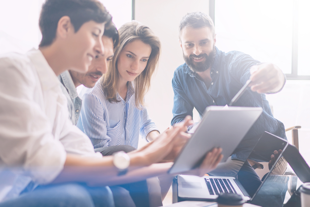 IT consultant sitting down with business professionals reviewing a detailed cybersecurity strategy on a device